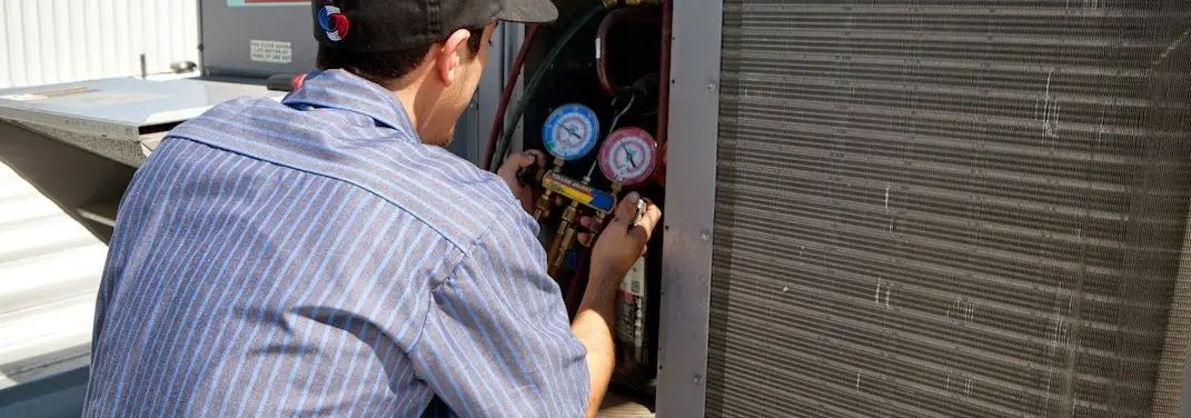 HVAC technician servicing a condenser unit in Hailey